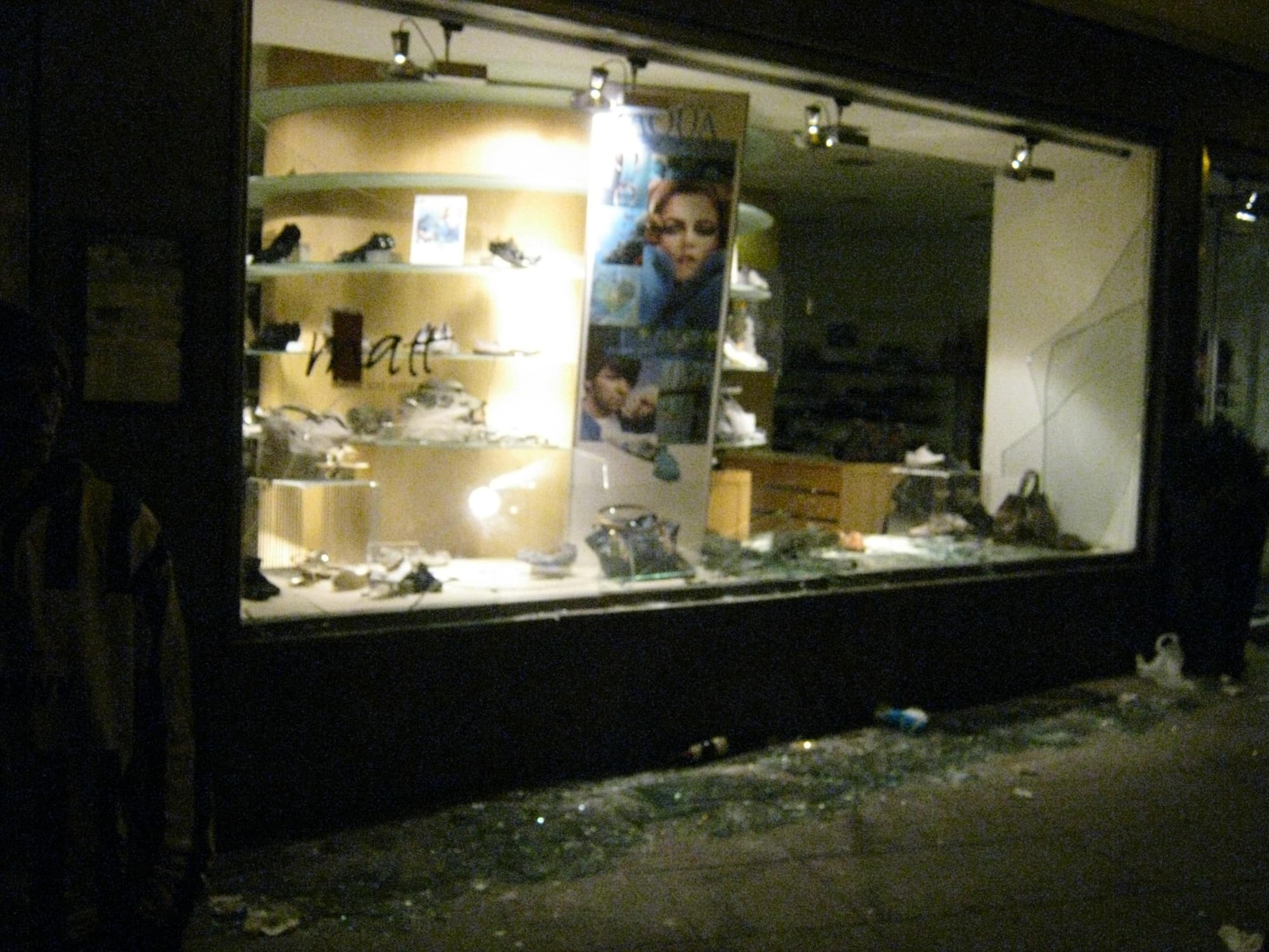 Vitrine de magasin brisée la nuit, éclats de verre devant l'étalage