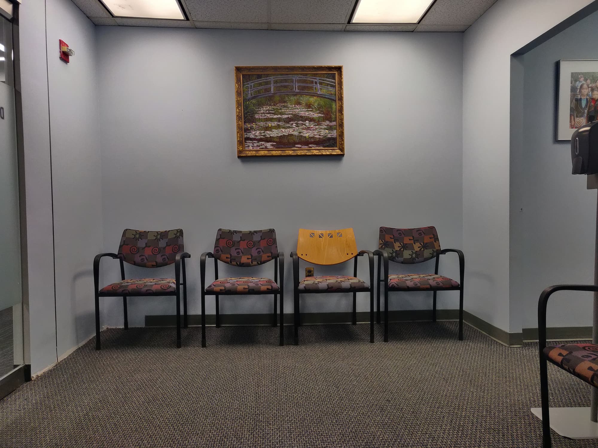 Salle d'attente d'un cabinet avec quatre chaises alignées contre un mur